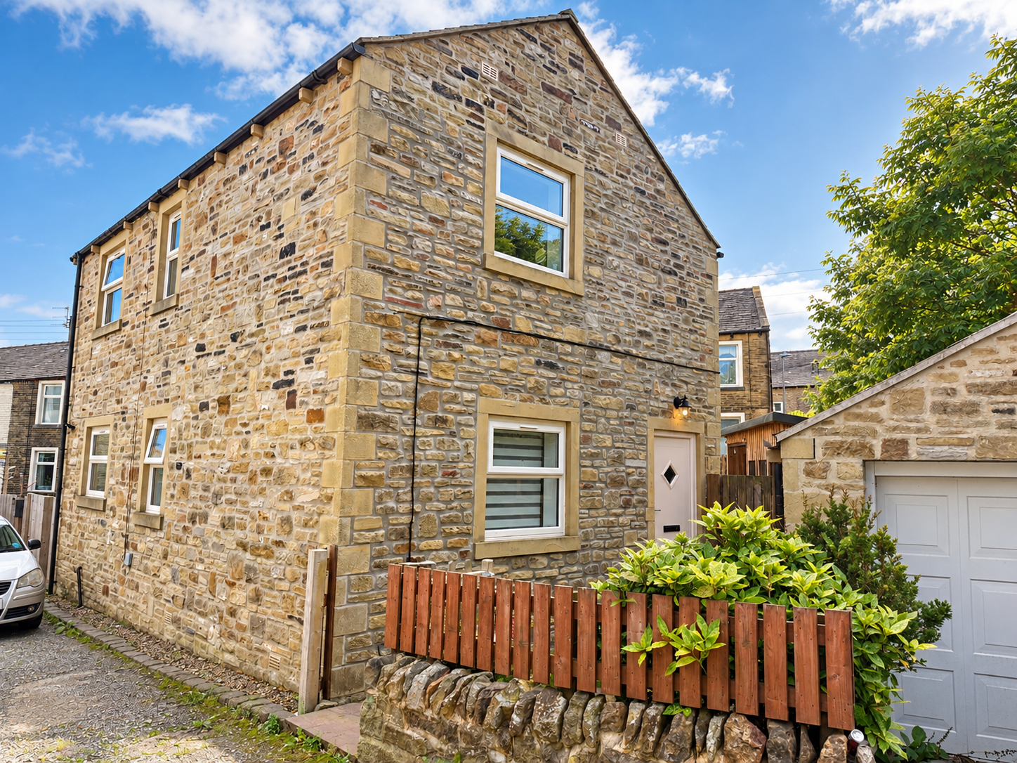 A stone-built house with an attached garage and front garden